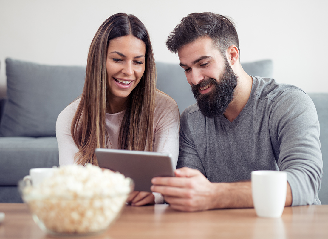 Read Our Reviews - Happy Couple Looking at a Tablet Together